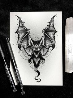 a black and white drawing of a dragon with wings on it's back, next to two markers