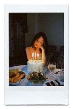 a woman sitting in front of a cake with lit candles