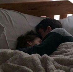 a man and woman laying in bed under a blanket