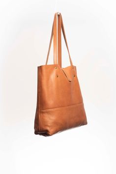 Natural-grained leather unlined tote bag. It features two open exterior pockets and one internal zippered pocket. It comes with fixed leather handles. It’s held shut by a sturdy snap closure. Smooth Grain Hobo Bag Tote For Work, Smooth Grain Tote Hobo Bag For Work, Smooth Grain Hobo Bag In Tote Shape For Work, Workwear Bucket Bag With Leather Lining, On-the-go Smooth Grain Tote Bucket Bag, Textured Leather Bucket Bag Tote For Everyday Use, Textured Leather Tote Bucket Bag For Everyday Use, Everyday Textured Leather Tote Bucket Bag, Everyday Textured Leather Bucket Bag With Double Handle