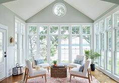 a living room filled with white furniture and windows covered in lots of glass door frames