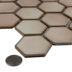 a penny sitting on top of a white and brown mosaic tile floor with hexagonal tiles