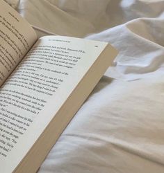 an open book sitting on top of a bed