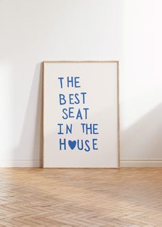 the best seat in the house print on a wall next to a wooden floor with a plant