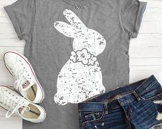 a t - shirt with the image of a rabbit and flowers on it, next to jeans