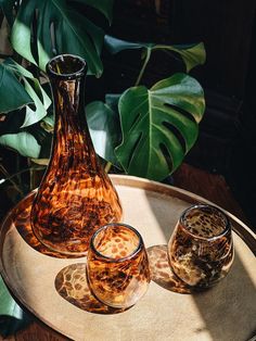 three glass vases sitting on top of a metal tray