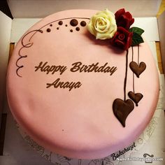 a pink birthday cake with chocolate hearts and roses on it's side that says happy birthday any name here