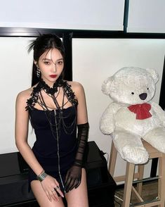 a young woman posing next to a white teddy bear