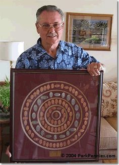 an older man holding up a painting in his living room