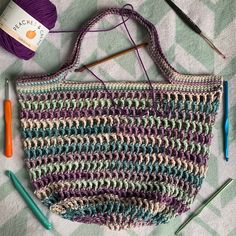 a crochet bag with yarn and knitting needles next to it