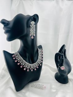 A dazzling Pink gemstone takes centerstage in this exquisite necklace set. Paired elegantly with Cubic Zirconia adding a touch of timeless glamor, mimicking the sparkle of genuine diamonds. The necklace gracefully drapes around the neck creating a captivating and versatile accessory for any occasion. Unique features:  Gemstone and Cubic Zirconia meticulously cut and polished radiates an enchanting brilliance. Style:  Ethnic and urban wear. Dress Compatibility:  Any dress with a V neckline or plu Diamond White Sterling Silver Jewelry Sets For Party, Party Jewelry Sets In White Gold With Sparkling Stones, Party Jewelry Sets With Sparkling Stones In White Gold, Party White Gold Jewelry Sets With Sparkling Stones, Dazzling Diamond White Jewelry Sets With Matching Earrings, Glamorous Diamond Jewelry For Celebration, Dazzling Sparkling Jewelry For Celebration, Sparkling Dazzling Jewelry For Celebrations, Dazzling Diamond White Jewelry Sets For Party