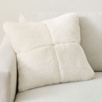 a white couch with two pillows on it's back and one pillow that is folded over