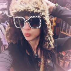 a woman wearing sunglasses and a fur hat