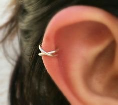 a woman's ear is shown with a tiny silver ring on it