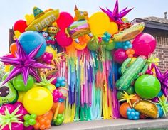 a bunch of balloons and streamers on the side of a building in front of a house