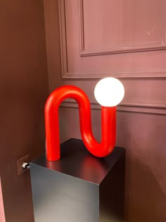 a red lamp sitting on top of a metal block in front of a door with a white light