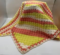 a crocheted blanket sitting on top of a white table next to a pillow