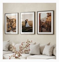 three framed pictures hang on the wall above a couch with pillows and flowers in front of them