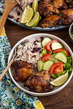 two plates with chicken, rice and vegetables on them next to a bowl of salad