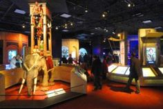 an elephant statue is on display in a museum with people looking at it and walking around