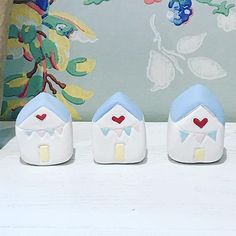 three little houses with hearts painted on them sitting in front of a floral wallpaper