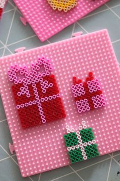 two pieces of bead art sitting on top of a pink place mat next to each other