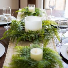 the table is set with candles and greenery for an elegant touch to the place setting