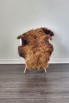 a brown chair sitting on top of a hard wood floor next to a white wall