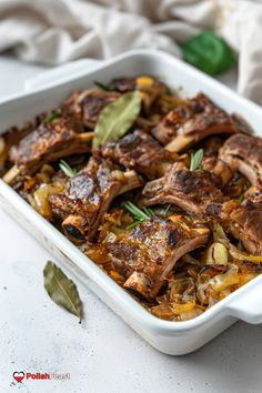 a casserole dish with meat and vegetables in it on a white tablecloth