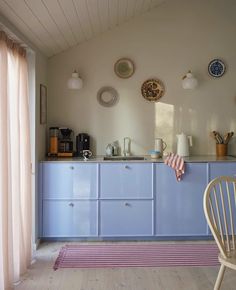 a kitchen with blue cabinets and pink rugs on the floor, along with plates hanging on the wall