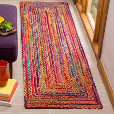 a living room with a purple couch and colorful rug