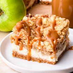 a piece of cake with caramel drizzle on top and an apple in the background