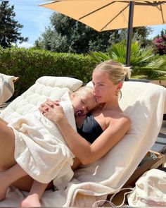 a woman laying on top of a white towel next to a baby in a chair