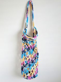 a multicolored crocheted bag hanging on a wall with white walls in the background