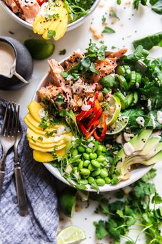 a white bowl filled with green vegetables next to some silverware and utensils