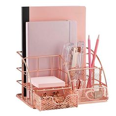 a pink desk set with pens, pencils and paper in the holder next to it