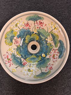 a bowl with flowers painted on it sitting on a table next to a black surface