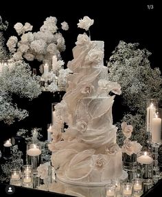 a wedding cake is surrounded by candles and flowers