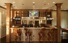 an image of a home bar in the middle of a living room with tvs on