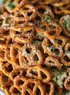 a plate full of pretzels covered in powdered sugar and sprinkled with parsley