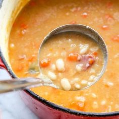 a ladle full of beans and carrots in a pot