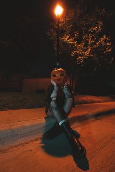 a person sitting on the side of a road with a jack - o'- lantern