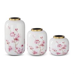 three white vases with pink flowers painted on the sides and gold rimmed lids