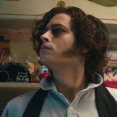 a man with curly hair wearing a white shirt and black suspenders looking off into the distance