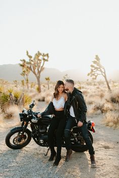 a man and woman sitting on a motorcycle in the desert