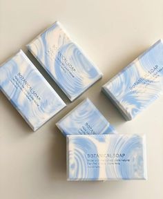 four soap bars sitting next to each other on top of a white table with blue swirls