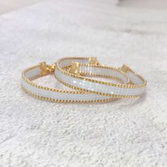 two white and gold bracelets sitting on top of a table