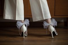 a pair of white high heeled shoes with bows