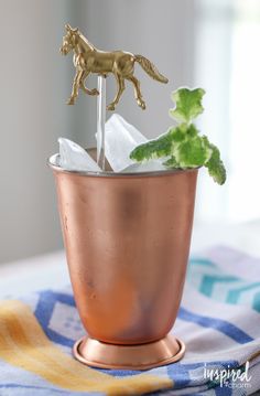 a horse figurine on top of a copper cup filled with ice and mint