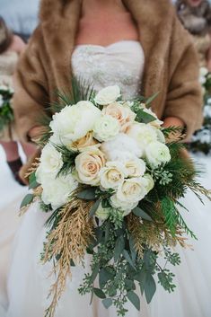 a bridal holding a bouquet of white flowers and greenery